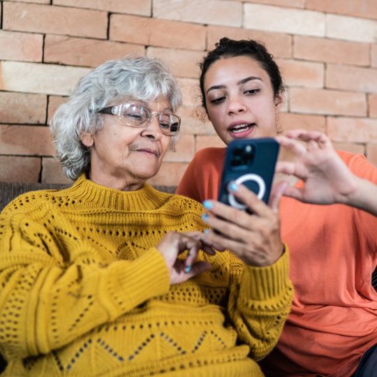 73_9282_28Feb2024141612_Teenager helping senior woman to use the mobile phone 540px.jpg
